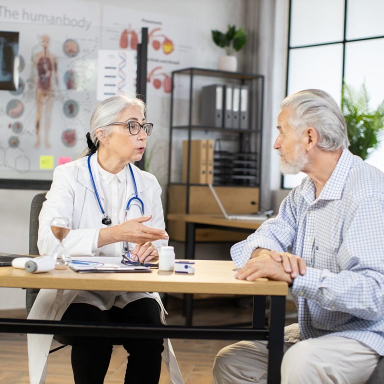 Older man attending routine GP appointment discussing prostate cancer symptoms with doctor