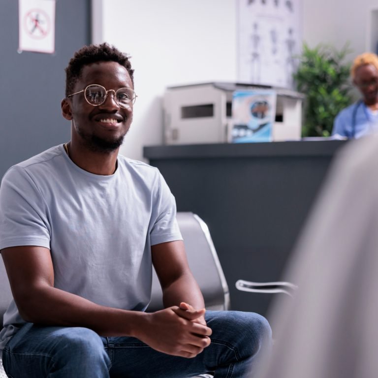 Smiling man in a grey t-shirt waiting in a clinic reception before a prostate cancer appointment